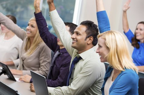 Diverse businesspeople raising hands during meeting or conference